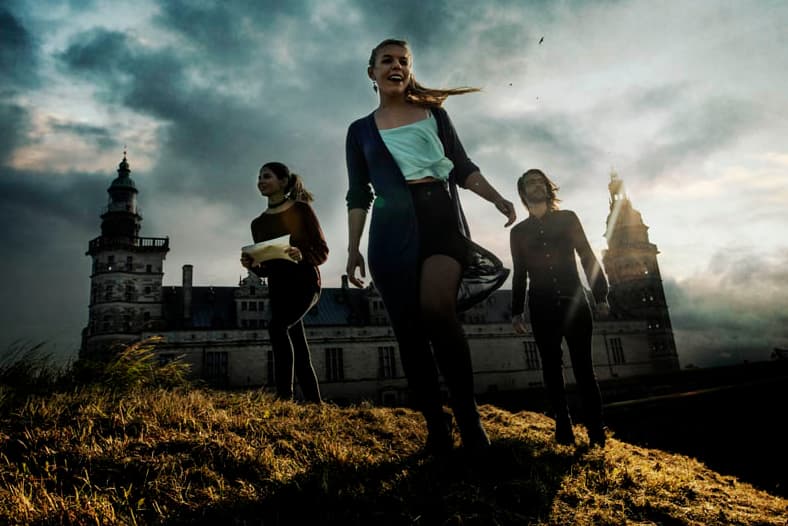 Three participants are walking along the ramparts in front of Kronborg Castle